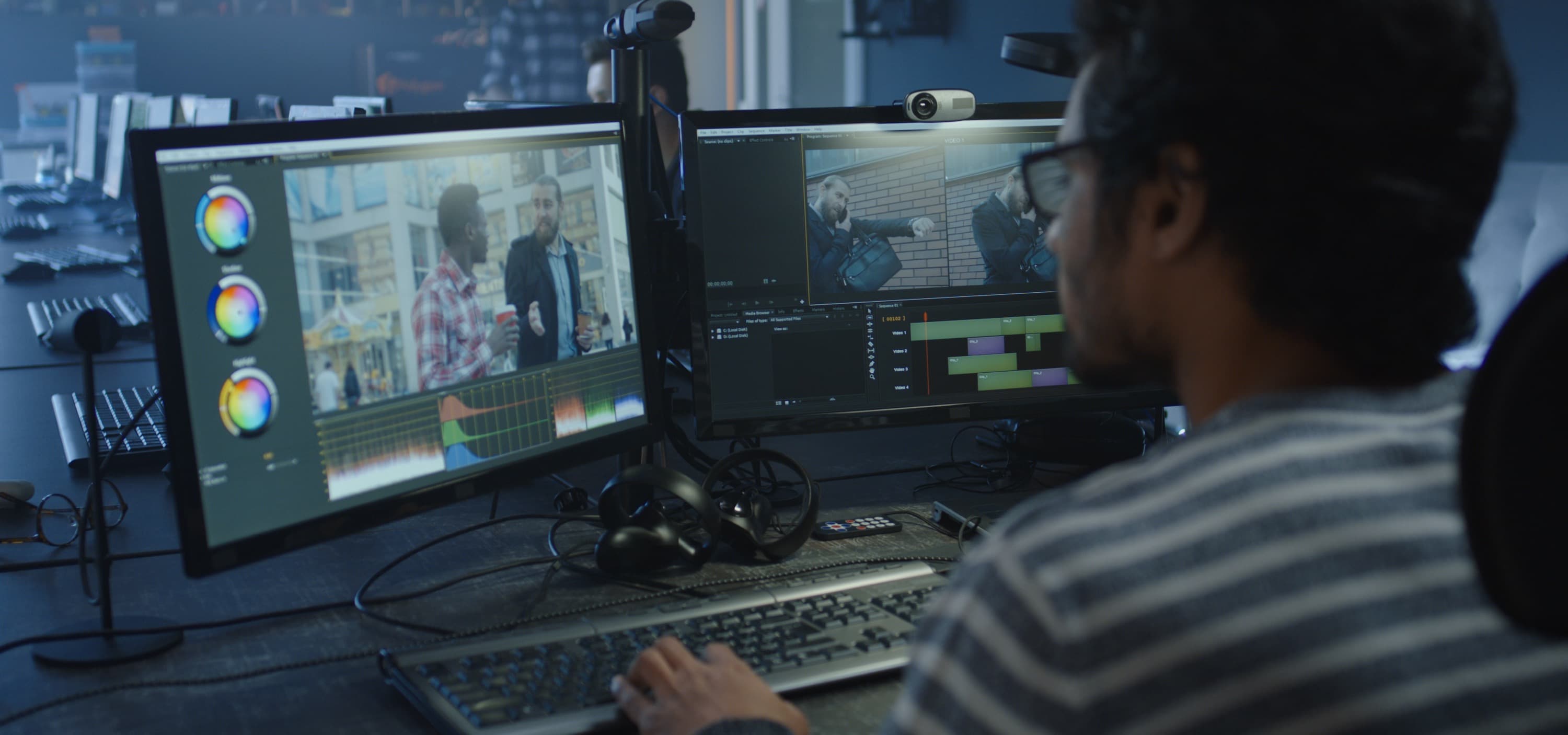 A man sitting at a video editing workstation with two monitors.